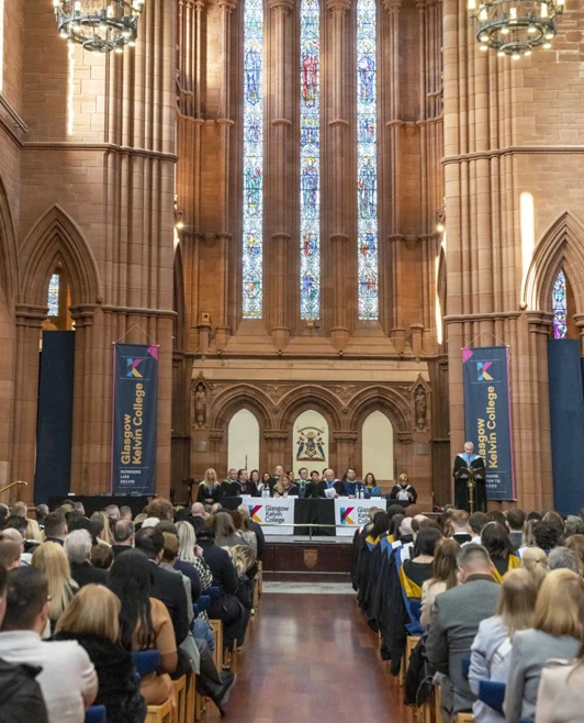 Wide view of the graduation stage inside the church with banners and college staff seated at the front. Wide view of the graduation stage inside the church with banners and college staff seated at the front.